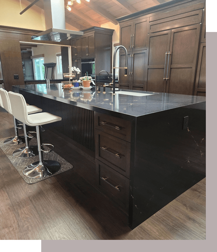 A kitchen with black counter tops and white stools.