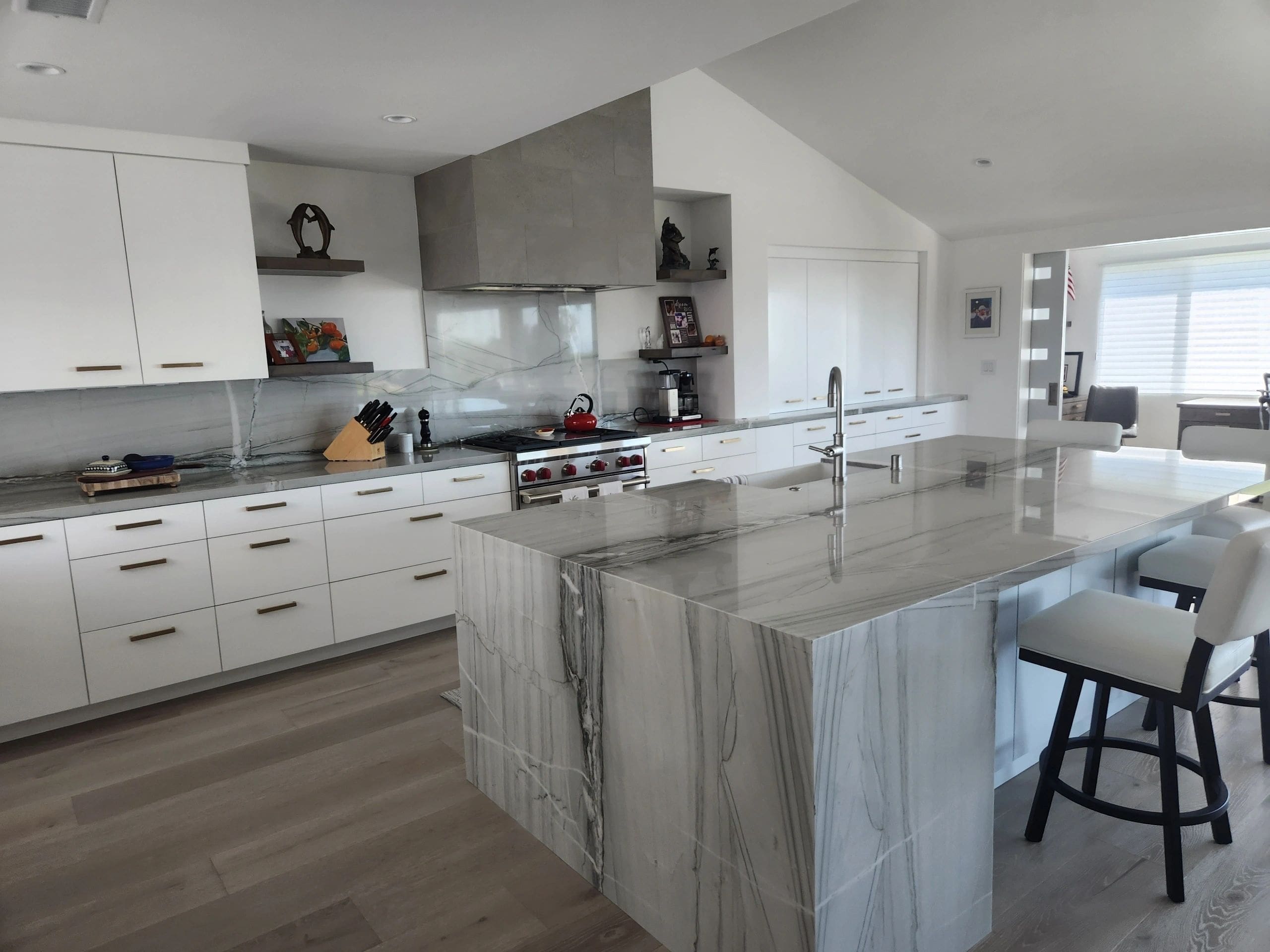 A kitchen with marble counter tops and white cabinets.