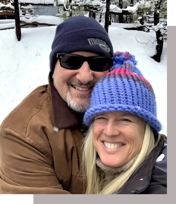 A man and woman smiling for the camera in the snow.