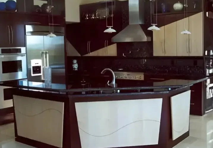 A kitchen with black and white cabinets, sink and counter.